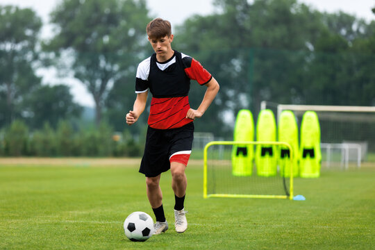 Youth Soccer Training. Young Player on Drills, Exercises And Match Preparation Training Session. Soccer Player Running With Ball. Training Goal and Football Training Air Mannequins in Background
