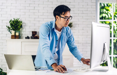 Young creative man relaxing using desktop computer working and video conference meeting online chat...