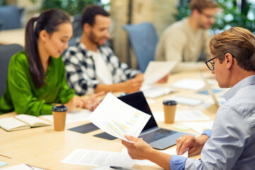 Brainstorming meeting. Group of multiracial people sitting at the desk in the modern coworking space or office and working on project together