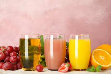 Glasses of delicious juices and fresh fruits on white wooden table