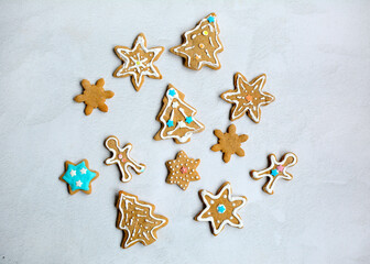 Top view of delicious homemade gingerbread cookies in the shape of stars, trees, Christmas men on a light background. Closeup