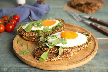 Delicious sandwiches with arugula and fried egg on blue wooden table