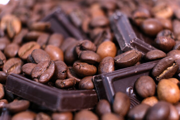 Close-up of dark roasted coffee beans and chocolate background.