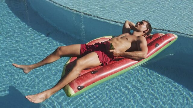 Young Man Sunbathing On Watermelon Pool Float