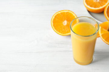Glass of orange juice and fresh fruits on white wooden table. Space for text