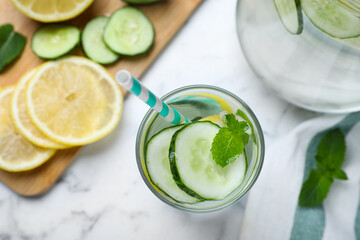Refreshing water with cucumber, lemon and mint on white marble table, flat lay