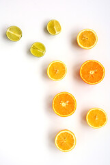 The layout of whole and sliced oranges, lemons, lime on a white plate on a white background