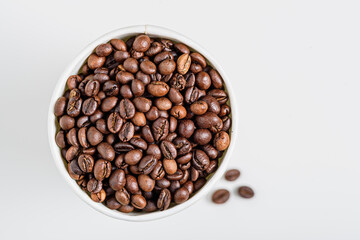 roasted coffee beans in white cup on white background