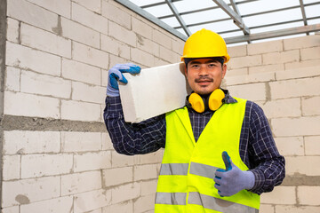 Worker reassure holds autoclaved aerated bricks in construction site, Concept proposes to use...