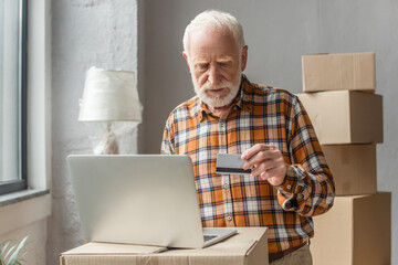 senior man making online purchase with credit card and laptop