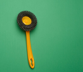 yellow plastic brush for cleaning the house on a green background