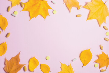 Naklejka na ściany i meble Autumn fallen leaves and medicines on pink background.