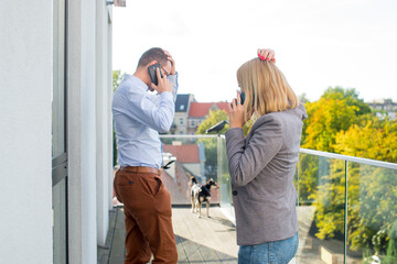 The woman and the man on the terrace are talking on the phone separately. Businesswoman and businessman with mobile phone on terrace. Work from smartphone. Covid theme. Pandemic theme.