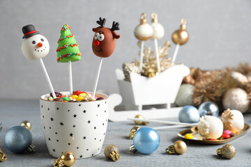 Delicious Christmas themed cake pops and festive decor on wooden table against grey background