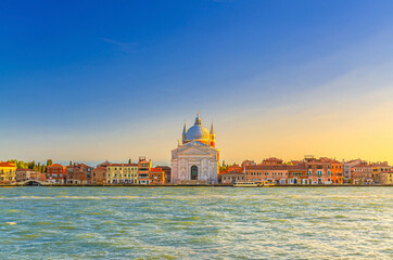 Fototapeta premium Chiesa del Santissimo Redentore catholic church and row of buildings on fondamenta embankment of Giudecca island canal in Venetian Lagoon, sunset view from Venice city, Veneto region, Northern Italy