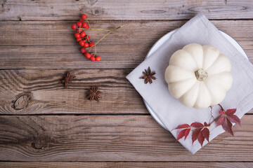 White pumpkin in a plate on wooden table, autumn background, flat lay