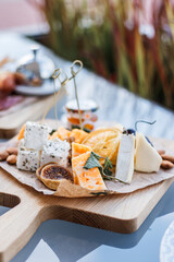 Assorted cheeses on a wooden cutting board. Traditional Italian platter with appetizers. Brie cheese, cheddar slices, gogonzola, parmesan, nuts, figs