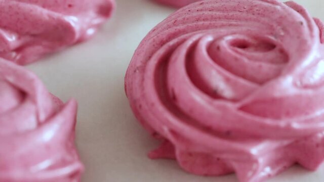 Squeezing pink cream out of a baking bag to make dessert