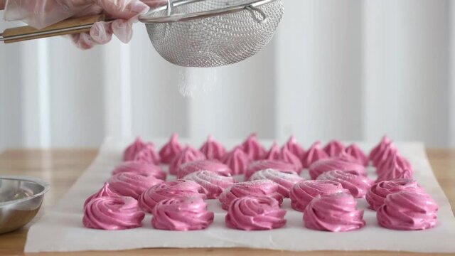 Sprinkle icing sugar on a pink dessert