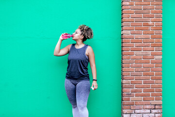 curly-haired woman and sportswear on a green wall