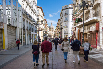 Alfonso I pedestrian street with the Basilica of Our Lady of Pilar in the background during the weekend of celebration of the patron saint festivities with people walking 