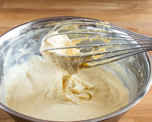 Dough on a whisk for flour. Tin bowl