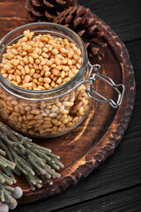 Pine nuts in a glass dish on a dark background with nuts scattered around