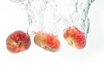 Bunch of doughnut peaches isolated on white, splashing into water.