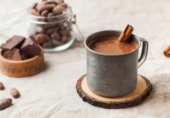 Hot chocolate in a metal mug with a cinnamon stick on the tablecloth. Copy space