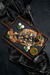 Fish dishes cooking preparation with dorado in backing form in shape of fish with healthy vegetables on dark rustic background with ingredients, top view. Seafood concept.