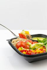 Healthy salad with tuna and vegetables, fork and white background