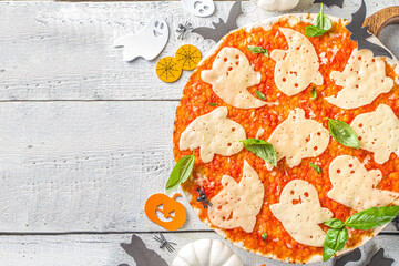 Halloween funny pizza. Halloween party recipe, Creative idea for Halloween pizza`s with ham and cheese ghosts, monster, spiders, white wooden background with Halloween decorations