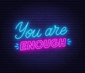 Fototapeta na wymiar You are enough neon quote on a brick wall. Inspirational glowing lettering.
