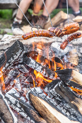 Friends roast sausages over an open fire outdoors