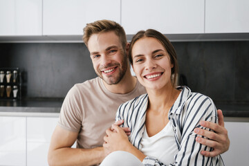 Young beautiful caucasian couple smiling and hugging together at home