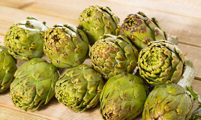 Obraz premium Fresh ripe green artichokes on light wooden background