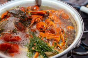 Crayfish are boiling in a large saucepan with dill on the fire