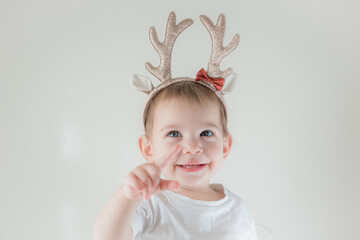Little infant girl with shiny glitter rain deer horns costume. New year and christmas party celebration. Christmas holidays.