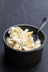 Potted aged Blue stilton cheese on black stone background