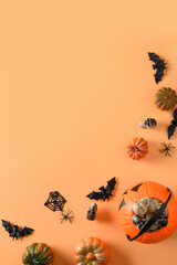 Halloween banner of fun party decorations, pumpkins, candy bowl, bat, skulls, spider on orange. Top view, flat lay.