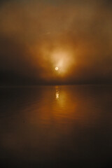 Fototapeta na wymiar Amanecer entre la bruma, con el Sol reflejado en el agua