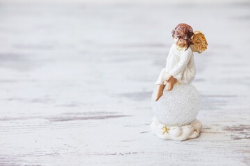 Ceramic figure of angel on light background. Copy spase.