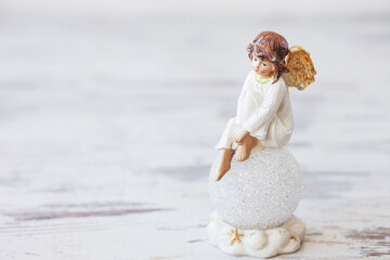 Ceramic figure of angel on light background. Copy spase.
