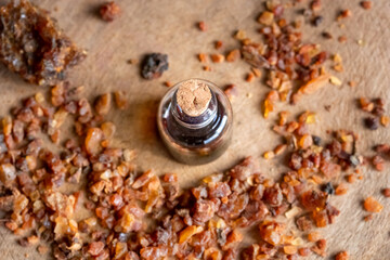 A bottle of myrrh essential oil with myrrh resin on a table