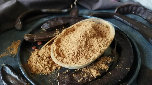 Dry carob pods and powder close up