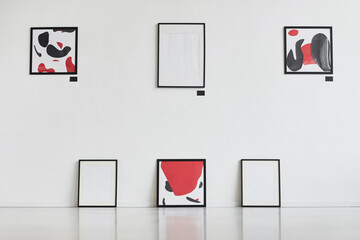 Graphic background image of modern abstract paintings with black and red hanging on white wall in...