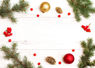 Merry Christmas frame and wallpaper. Happy New Year composition. Christmas balls, red berries, pine cones, fir branches on wooden white background