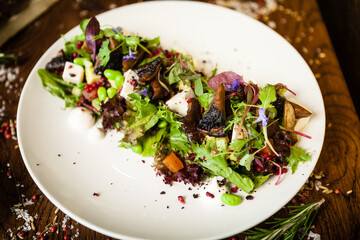 Fresh vegan salad. Avocado, couscous, melon, portobello, soybean, tofu on white plate. Delicious healthy mixed greens food closeup served on a table for lunch in modern cuisine gourmet restaurant.
