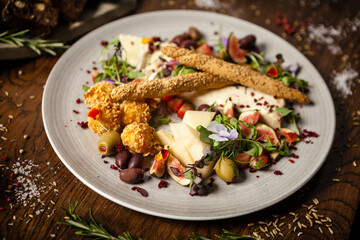 Cheese platter for two: Goat cheese cream, gorgonzola, camembert, grissini and fig jam. Delicious healthy Italian traditional food closeup served for lunch in modern gourmet cuisine restaurant