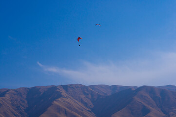 Fototapeta na wymiar Paragliding. A man flies on a parachute against the blue sky.